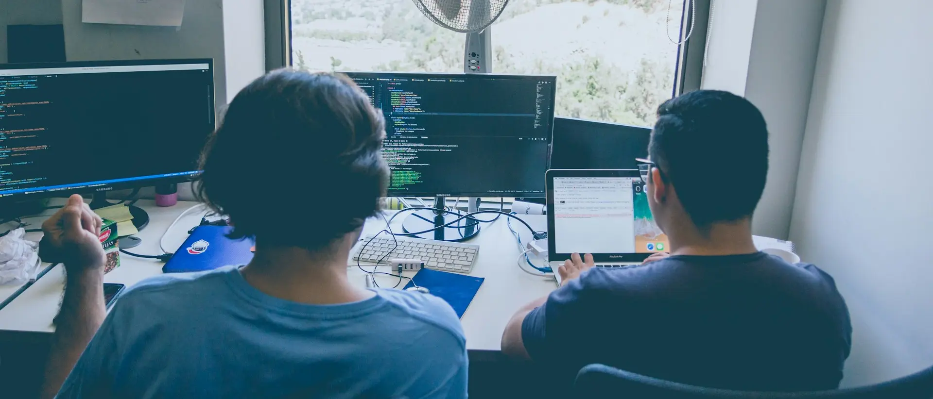 two men using computer and laptop